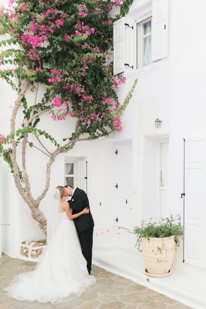 Bride and groom kissing in front of luxury villa in Mykonos, Greece