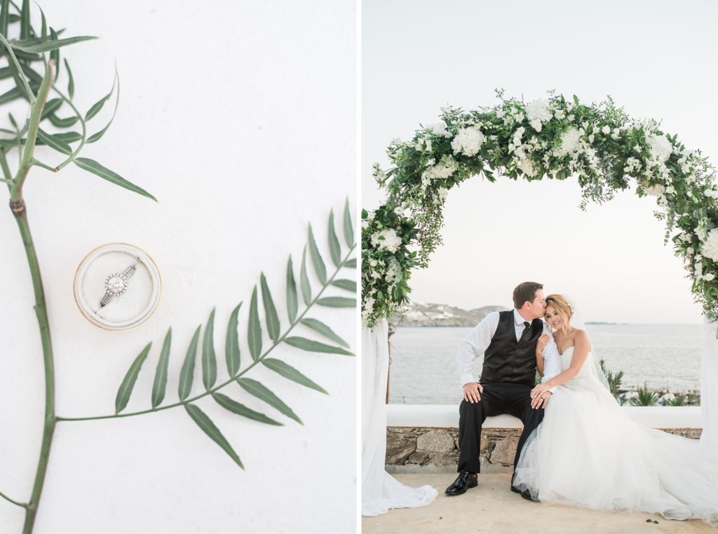 Groom kissing bride on the forehead under flower arch in Mykonos