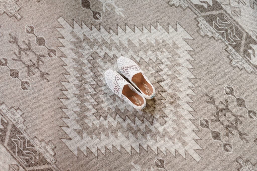 Groom's shoes placed in centre of boho carpet on morning of their wedding.