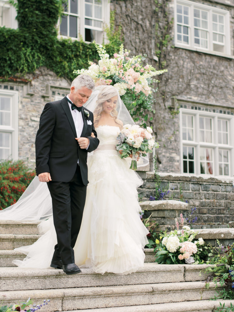 Bride and her father walk down the steps at her outdoor wedding at Luttrelstown Castle.