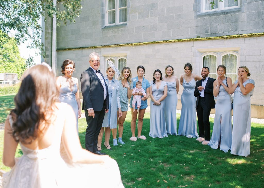 Bride reveals her wedding dress to her bridal party and father outside Dromoland Castle.
