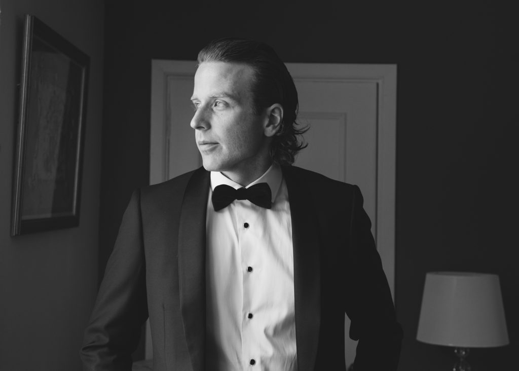 Black and white portrait of groom in suit on morning before his wedding at Dromoland Castle.
