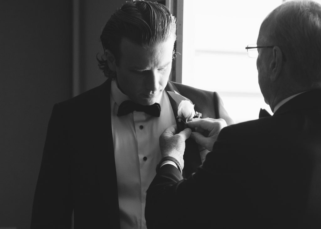 Black and white portrait of the groom having his father fix his boutonniere at The Inn at Dromoland.