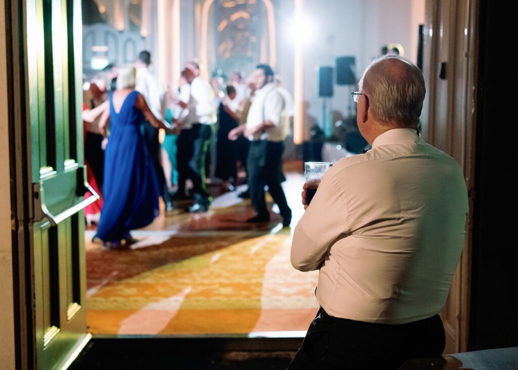 Father of the groom looks on proudly at everyone dancing at his son's wedding in Dromoland Castle Hotel.