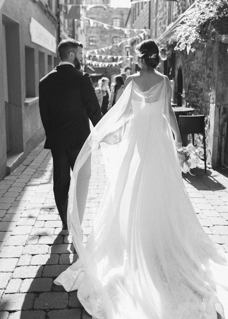 Romantic black and white portrait of bride and groom walking down Quay street in Galway city.