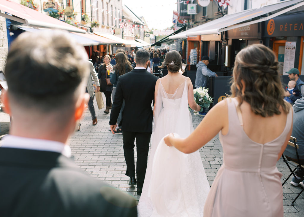Candid moment of bride and groom with maid of honour and best man walking through Galway city.
