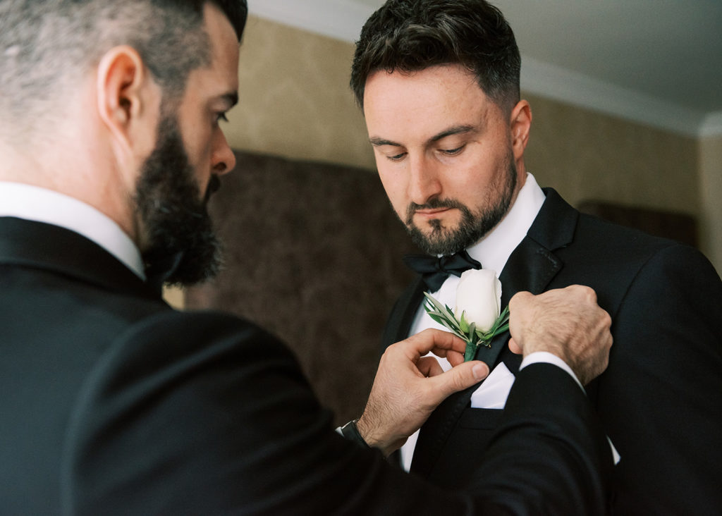 Groom and Best Man prepare wedding boutonnieres.