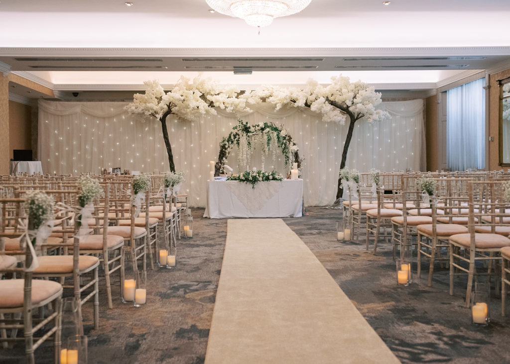 The Ardilaun Hotel's wedding ceremony room, with candles along aisle and floral arch.