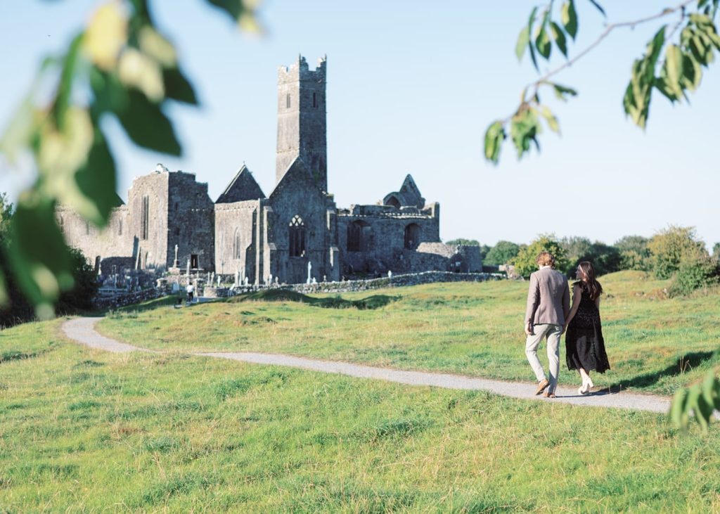 American couple walk together towards Quin Abbey for their engagement photoshoot.