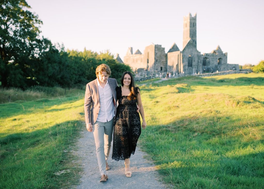 Irish Wedding Photography; couple walk towards camera after their engagement at Quin Abbey.