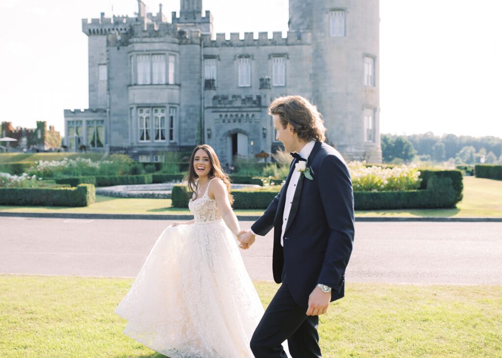 Epic portrait of Bride and Groom holding hands in front of Dromoland Castle Hotel on their wedding day.