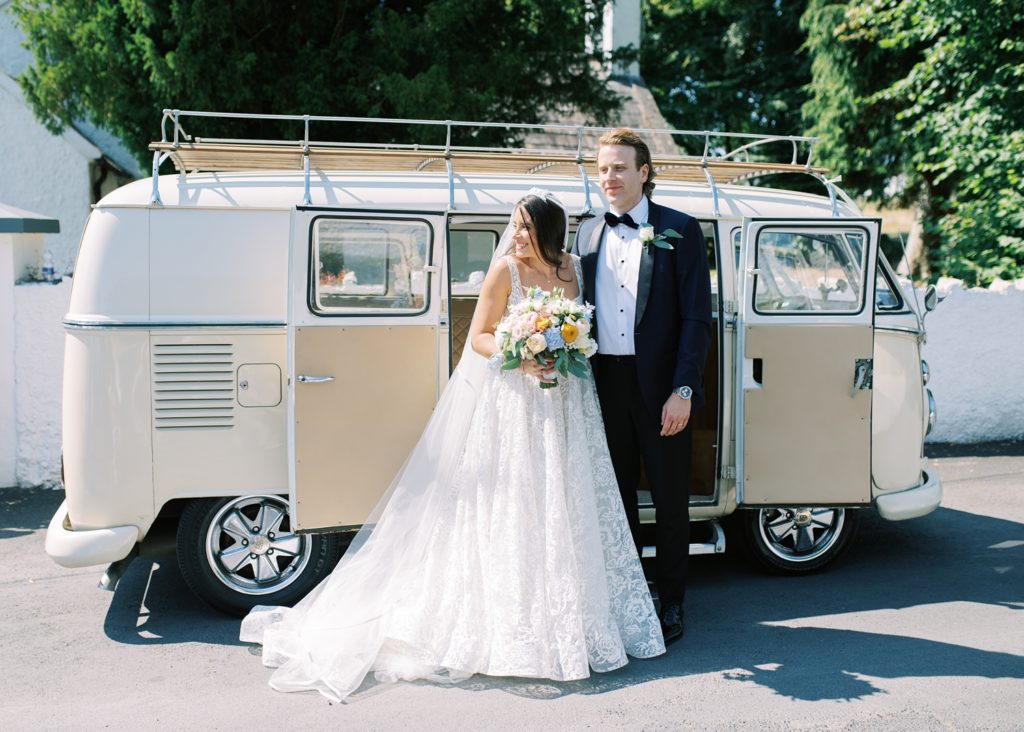 Bride and groom pose in front of their vintage VW camper van after their wedding ceremony in Clare, Ireland.