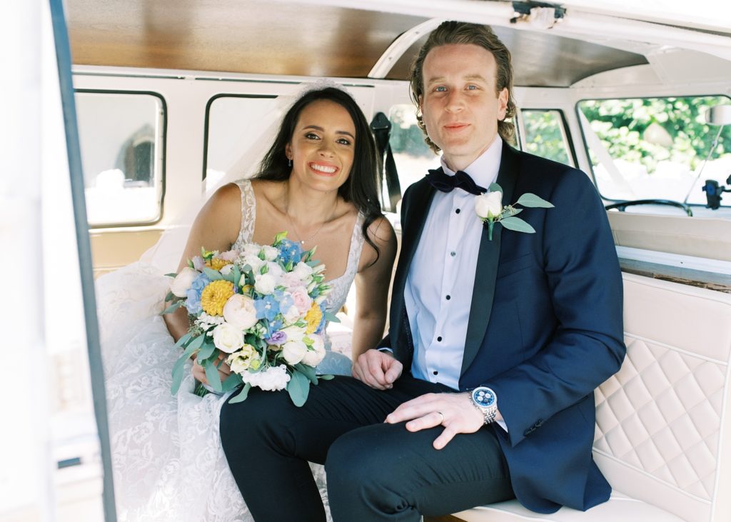 Bride and Groom sit together in their vintage VW camper van after their wedding ceremony.