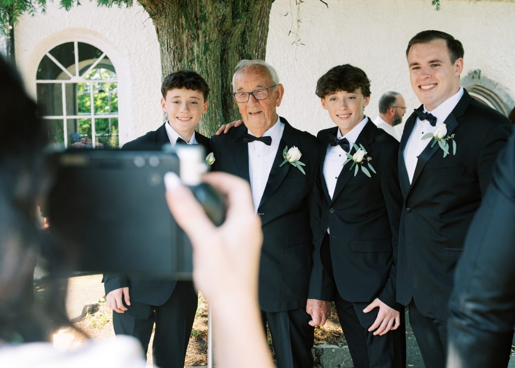 Brothers of the bride and their grandfather enjoy the excitement outside the church before the wedding ceremony.