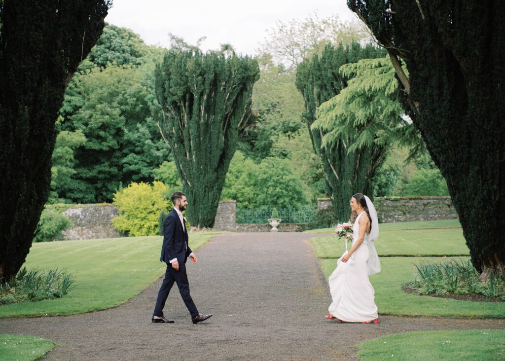 Husband and wife walk towards one another on their summer wedding day in the Walled Garden.