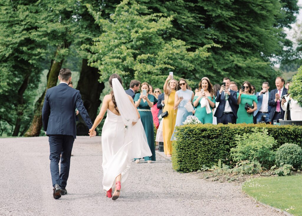 Guests cheer the return of the newlyweds after their wedding portraits in Tankardstown House.