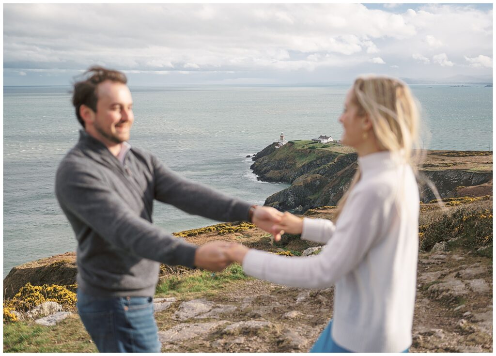 Engaged couple dancing in Howth with the beautiful Baily Lighthouse behind them.