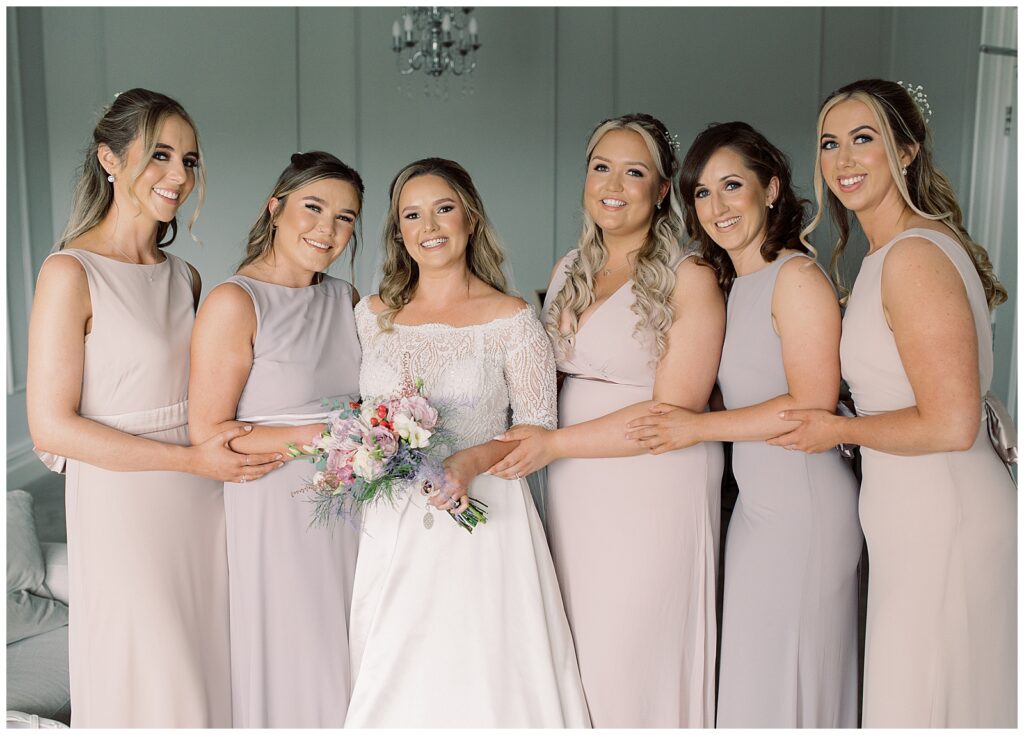 Gorgeous portrait of bridal party all together on the morning of the wedding, wearing matching cream coloured bridesmaids dresses.