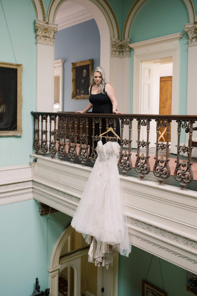 Bride observes her dress, hanging from the banister at Temple House in Sligo.