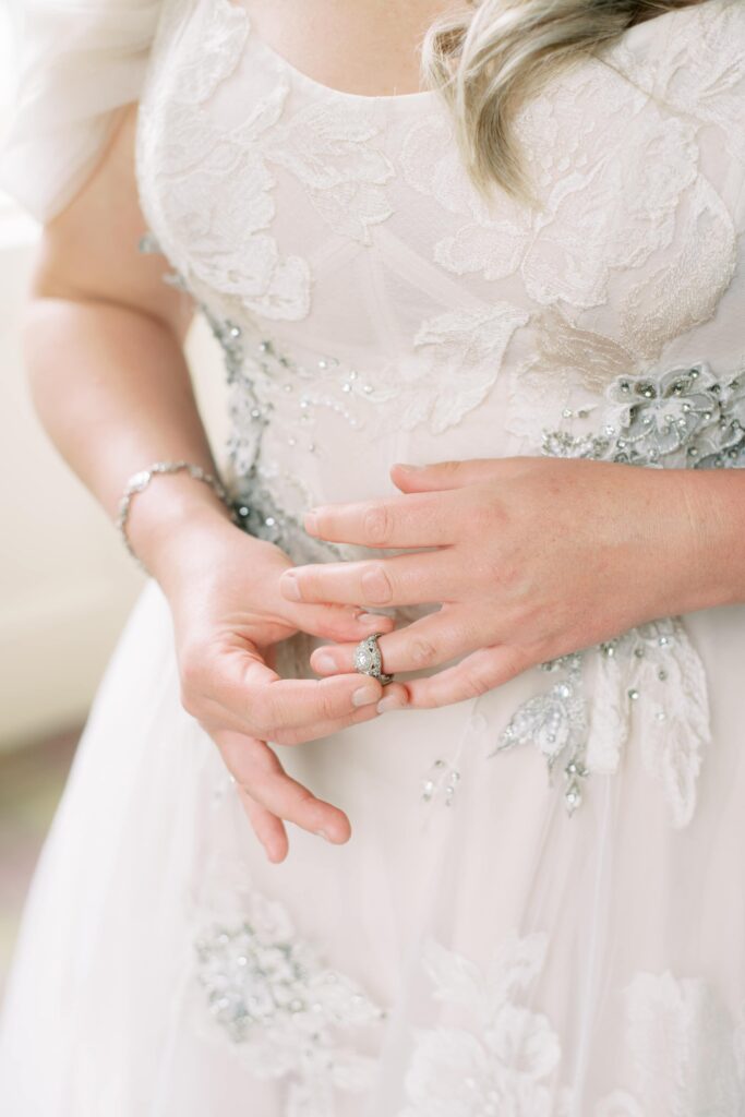 Detail of Bride's dress as she plays with her wedding ring.