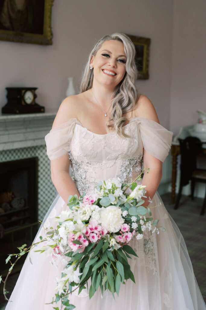 Portrait of the smiling Bride in her wedding dress with bouquet ready.
