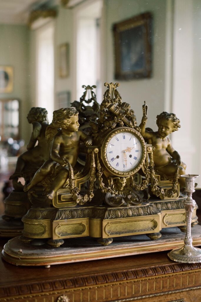 Antique clock on the mantlepiece, with a large mirror behind showing the length of the drawing room.