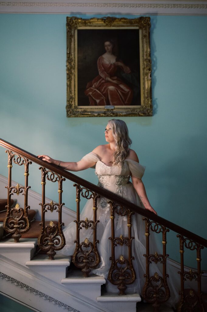 Dramatic evening portrait of the bride, lit by lamps, on the stairway in Temple House.