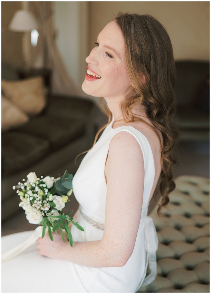 Bride sitting with bouquet and smiling at her family arriving to meet her.