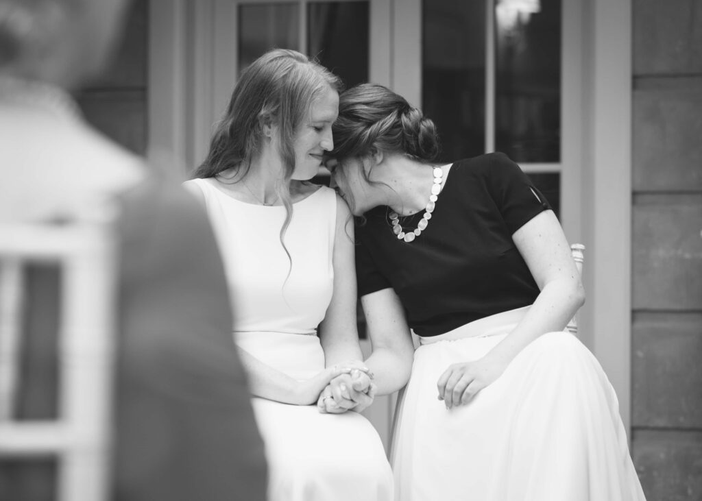 One bride kisses the other's shoulder during their same-sex wedding ceremony.
