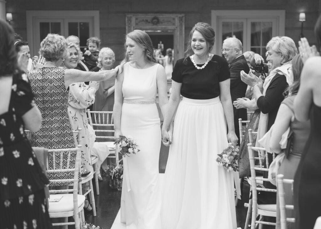 The two brides walk down the aisle together after their same-sex wedding ceremony is complete.
