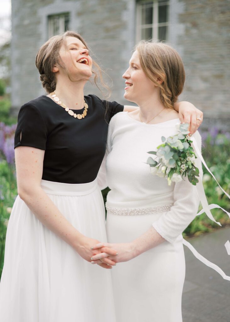 The two brides laugh with joy together in front of Tankardstown House's main entrance.