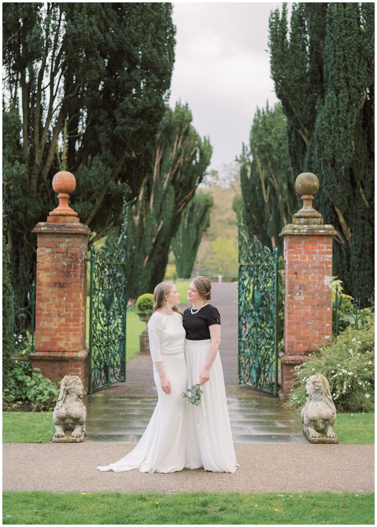 Same-sex wedding couple pose before the Walled Garden gate at Tankardstown.