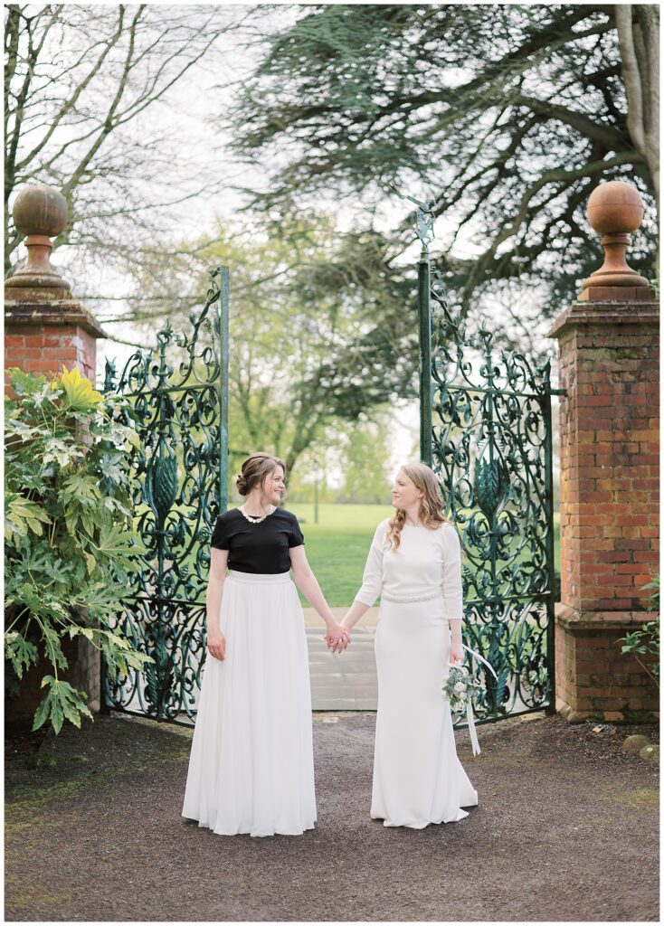 Same-sex couple hold hands in front of the Walled Garden gate at Tankardstown House.