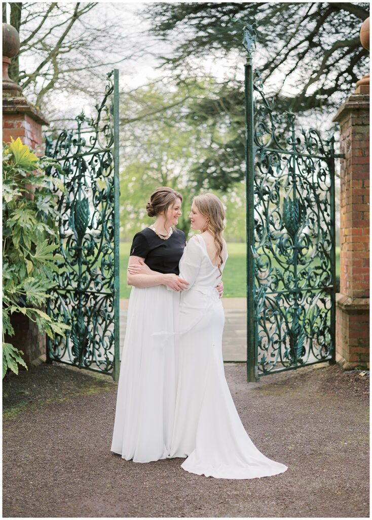 Same-sex wedding couple hold each other in front of the gates of the Walled Garden at Tankardstown House.