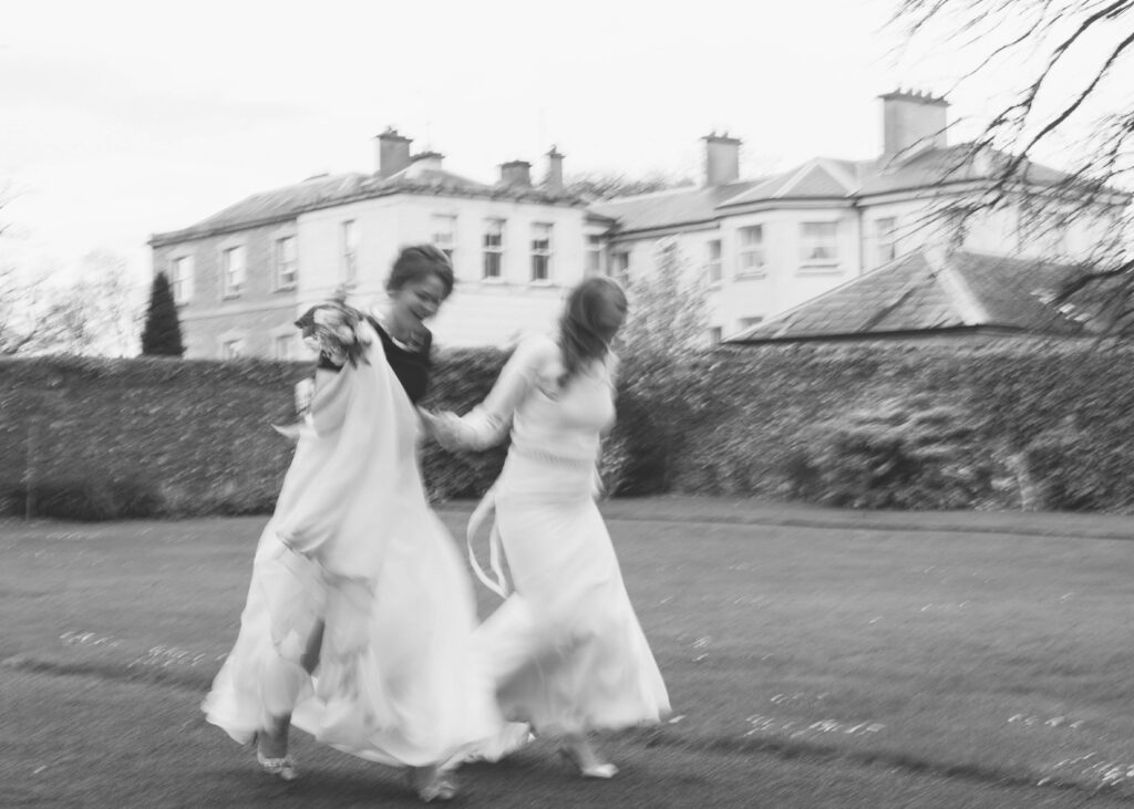 Black and white blurry motion photo of same-sex couple running in the Walled Garden at Tankardstown House.