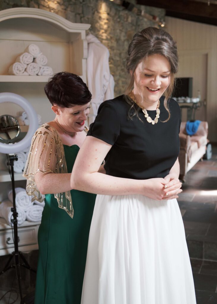 Bride's friend helps with the dress in the Secret Room, Tankardstown.