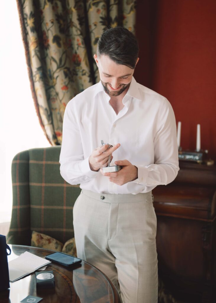 Portrait of Groom admiring a gift from his bride-to-be on the morning of his wedding.