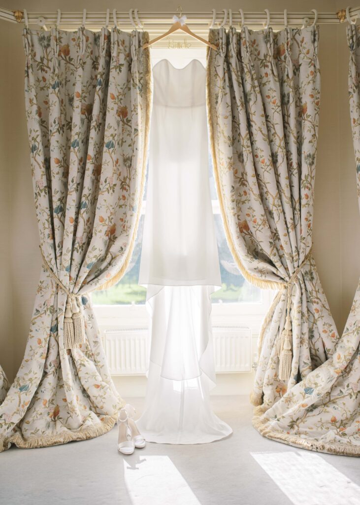 Autumn wedding at Tankardstown House, bride's dress hangs from the curtain rail glowing in the window.