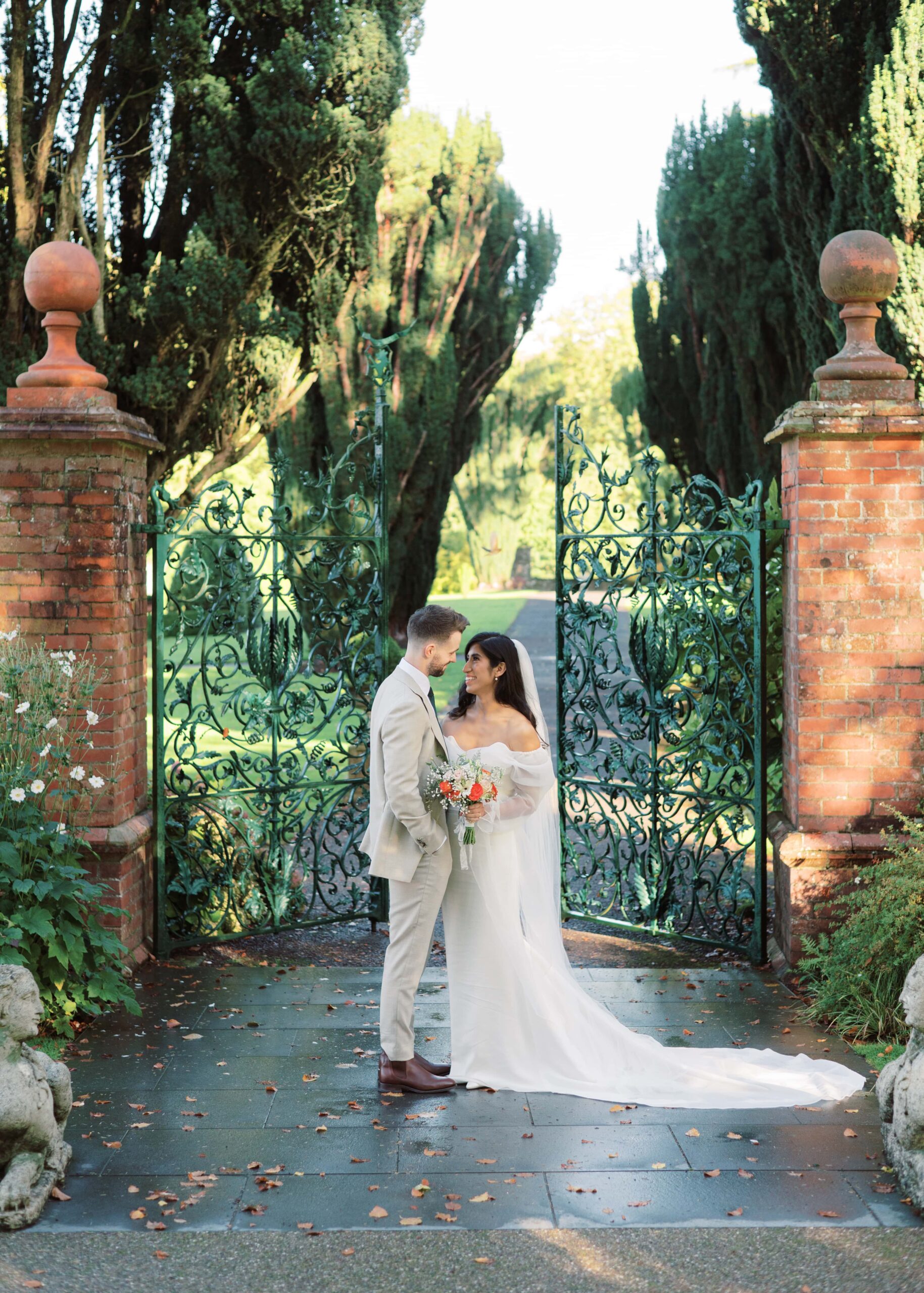 Newlywed couple pose in front of the gates of the walled garden in the autumn.