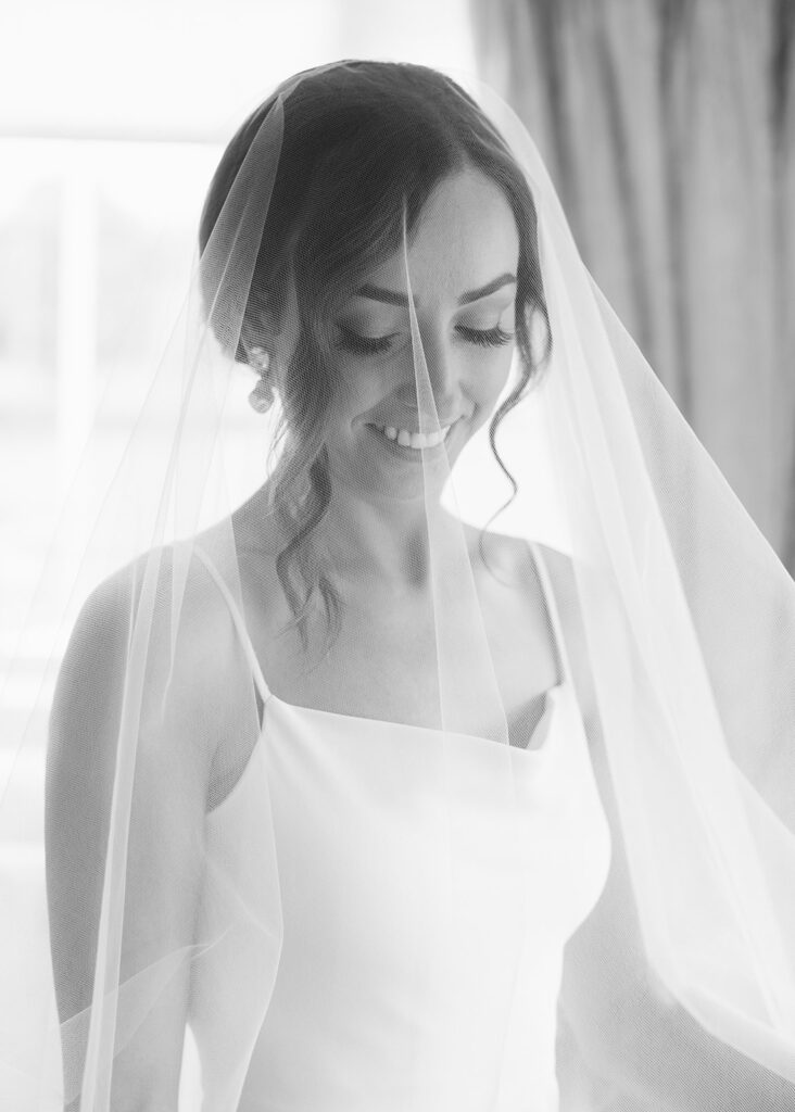 Black and white portrait of the bride under her veil in her family home.