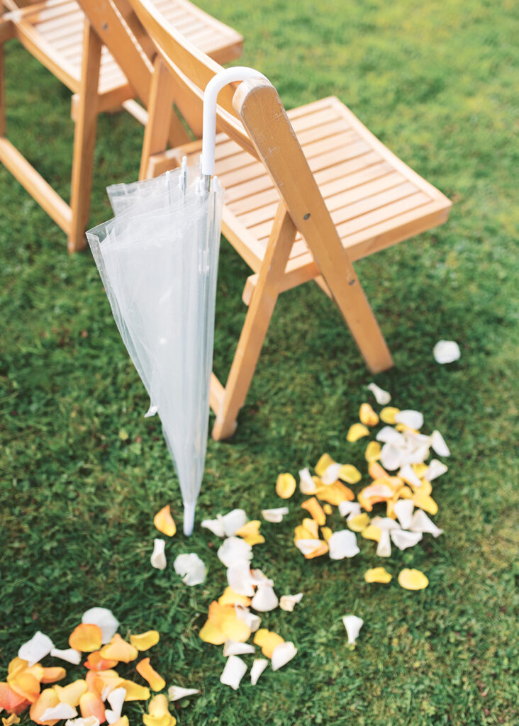 Detail photo of the garden wedding aisle with an umbrella and trail of flower petals.