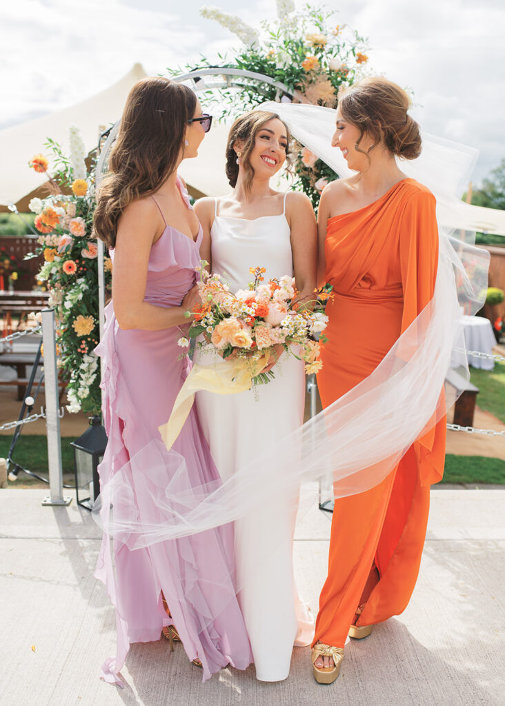 Bride and her two sisters share a moment together before the garden wedding ceremony.