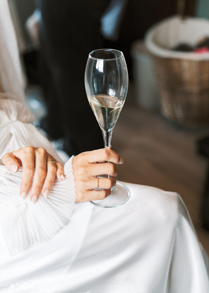 Close-up photo of the bride holing their champagne glass on the morning of the garden wedding.