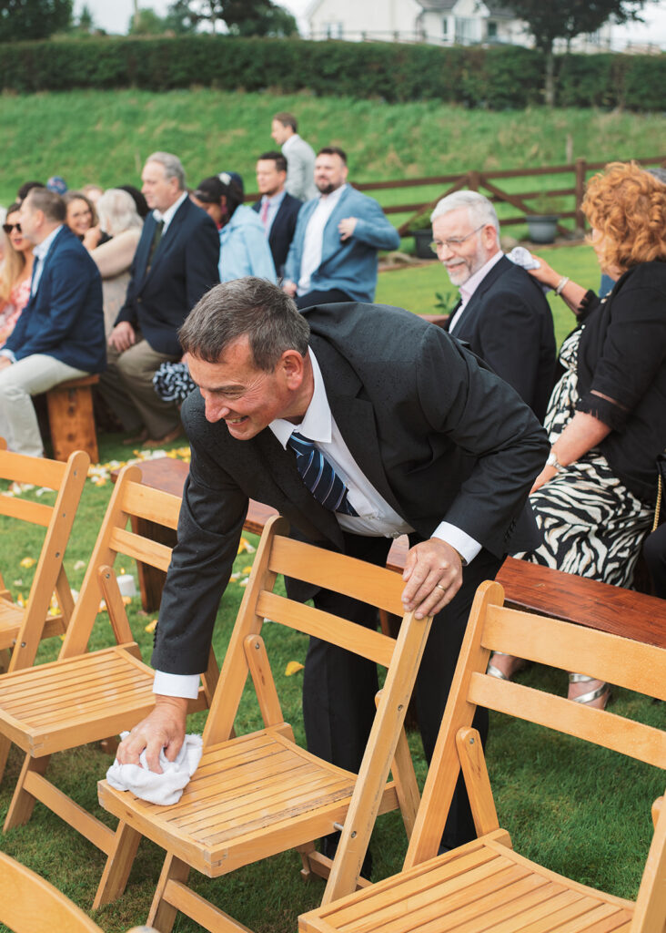 Guest kindly dries off the chairs for the bride's family during the wedding ceremony.