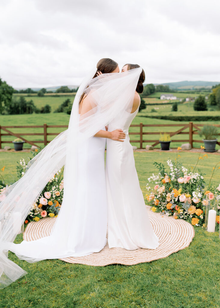 The married brides share a passionate embrace after their marriage as the wind kicks up her veil!