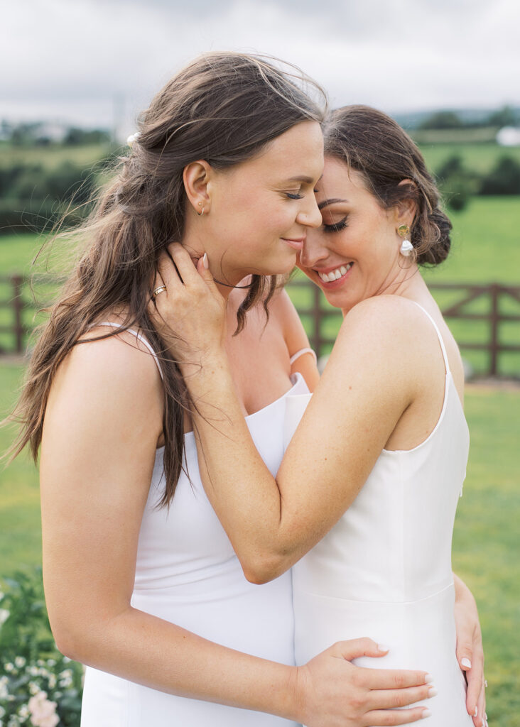 Close-up portrait of the two brides holding each other after their outdoor wedding ceremony.