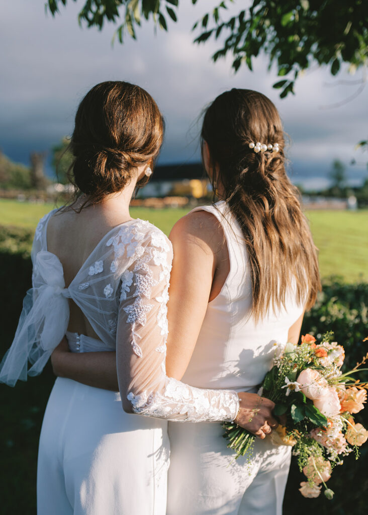 The two brides hold each other and look back at their wedding party at home in Monaghan.