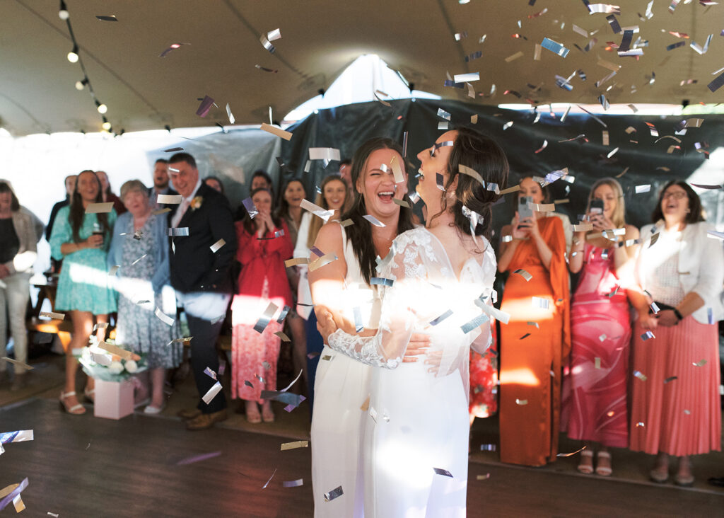 Confetti rains down on the two brides' first dance with cheers all around.